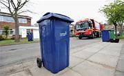 Blue household recycling bin with handles facing the road, ready for collection